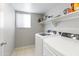 Functional laundry room with a washing machine, dryer, storage shelves, and a window for natural light at 891 E Windsor Dr, Gilbert, AZ 85296