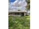 View of the backyard with a screened-in patio, lush lawn and mature trees at 11001 W Tonada Dr, Sun City, AZ 85351