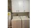 Functional laundry room featuring a washer, dryer, water heater and overhead cabinets at 11001 W Tonada Dr, Sun City, AZ 85351