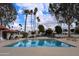 Community pool with inviting clear blue water, surrounded by palm trees and lounge chairs on a sunny day at 115 E Piping Rock Rd, Phoenix, AZ 85022