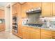 A close up on the kitchen showing the built-in oven and microwave, gas stovetop, and wood cabinets at 12820 W La Vina Dr, Sun City West, AZ 85375