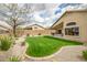 Well-maintained backyard featuring green grass, desert plants, and a covered patio at 16388 N 99Th Pl, Scottsdale, AZ 85260