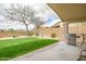 Landscaped backyard featuring a lawn, mature trees, and a covered patio with a stainless steel grill at 16388 N 99Th Pl, Scottsdale, AZ 85260