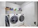 Efficient laundry room featuring modern, stacked washer and dryer units, and ample shelving for storage at 16388 N 99Th Pl, Scottsdale, AZ 85260