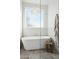 Bright bathroom featuring a standalone tub, wooden stool, and frosted window at 16409 N 62Nd Way, Scottsdale, AZ 85254