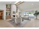 Living room featuring a stone fireplace, custom shelves, skylight, and sliding glass doors to the pool area at 16409 N 62Nd Way, Scottsdale, AZ 85254