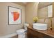 Charming powder room with a vessel sink, wooden vanity, and a framed abstract painting at 16409 N 62Nd Way, Scottsdale, AZ 85254