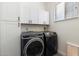 Functional laundry room featuring front-load washer and dryer, white cabinets, and overhead storage at 16617 S 16Th Ave, Phoenix, AZ 85045