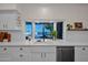 Bright, white kitchen featuring a bay window, stainless steel appliances, and stone countertops overlooking the outdoor pool at 19450 E Silver Creek Ln, Queen Creek, AZ 85142