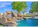 Close-up of a backyard pool's stunning rock waterfall feature at 19450 E Silver Creek Ln, Queen Creek, AZ 85142