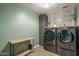 Modern laundry room featuring high-end washer and dryer, stylish wallpaper, and convenient storage at 21512 S 225Th Way, Queen Creek, AZ 85142