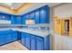 Kitchen featuring blue cabinetry, white countertops, ceramic backsplash and access to other rooms at 3022 E Weldon Ave, Phoenix, AZ 85016