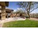 Backyard with built-in grill, stone fire pit, lush green lawn, and a mature tree at 9435 E Mohawk Ln, Scottsdale, AZ 85255