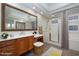 Bathroom with a large vanity, mirror, soaking tub and glass shower door with shower curtain at 9435 E Mohawk Ln, Scottsdale, AZ 85255