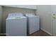 Laundry room featuring a white washer and dryer, tile floor, and storage cabinets at 9435 E Mohawk Ln, Scottsdale, AZ 85255