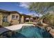 Sparkling pool with stone coping, mature trees, and views of the home's exterior at 9435 E Mohawk Ln, Scottsdale, AZ 85255