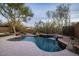 Backyard featuring a private pool with a stone waterfall and lush desert landscaping at 9435 E Mohawk Ln, Scottsdale, AZ 85255