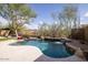 Backyard with a freeform pool, lush landscaping, stone waterfall feature, and mature trees at 9435 E Mohawk Ln, Scottsdale, AZ 85255