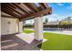 Outdoor patio area with a covered pergola, brick flooring, artificial grass and pool in background at 9675 E Cinnabar Ave, Scottsdale, AZ 85258