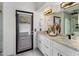 Modern bathroom with double sinks, marble countertops, and a shower area with decorative tiling and black framed door at 9675 E Cinnabar Ave, Scottsdale, AZ 85258