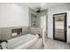 Bright bathroom featuring a soaking tub, glass shower, and modern tiles with black framed exterior access door at 9675 E Cinnabar Ave, Scottsdale, AZ 85258