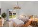 Bright bedroom featuring a king bed, sliding glass door to lawn, and decorative chandelier lighting at 9675 E Cinnabar Ave, Scottsdale, AZ 85258