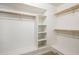 Spacious walk-in closet with built-in shelves, rods, and a bench for ample storage, all painted in white at 9675 E Cinnabar Ave, Scottsdale, AZ 85258