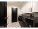 Bright laundry room with a black front-load washer and dryer, white cabinets and patterned floor at 9675 E Cinnabar Ave, Scottsdale, AZ 85258