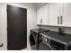 Laundry room with black washer and dryer and white upper cabinets at 9675 E Cinnabar Ave, Scottsdale, AZ 85258