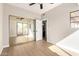 Bright bedroom featuring mirrored closet doors, light hardwood floors, and a ceiling fan at 9705 E Mountain View Rd # 1056, Scottsdale, AZ 85258