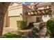 Home exterior featuring a garage, desert landscaping, and a covered entry with a pergola at 9705 E Mountain View Rd # 1056, Scottsdale, AZ 85258