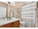 Neat bathroom featuring a white vanity, toilet, and shower with a striped curtain, offering a fresh and clean aesthetic at 12915 W Micheltorena Dr, Sun City West, AZ 85375