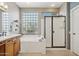 Bathroom showcasing a soaking tub next to a glass block window, and a glass-enclosed shower at 12915 W Micheltorena Dr, Sun City West, AZ 85375