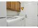 Bright laundry room featuring wood cabinetry and modern, front-loading washer and dryer for convenient chores at 12915 W Micheltorena Dr, Sun City West, AZ 85375