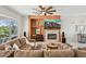 Cozy living room featuring a fireplace, entertainment center, comfortable sofa and natural light at 12915 W Micheltorena Dr, Sun City West, AZ 85375