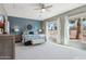 Bright main bedroom with a blue accent wall, a ceiling fan, and large windows showcasing the outdoor landscape at 12915 W Micheltorena Dr, Sun City West, AZ 85375