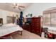 Bright bedroom features a ceiling fan, window with blinds, and dark wood furniture at 13331 W Romain Ct, Litchfield Park, AZ 85340
