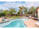 Backyard swimming pool with tiled edges, stone waterfall feature, and patio furniture around pool deck at 13331 W Romain Ct, Litchfield Park, AZ 85340
