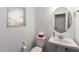 Cozy half bath with toilet, pedestal sink, round mirror, and window with natural light at 14175 W Bronco Trl, Surprise, AZ 85387
