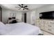 This bedroom includes gray walls, a ceiling fan, a television on a dresser, and a connected bathroom at 14175 W Bronco Trl, Surprise, AZ 85387