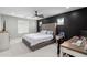 This bedroom features a tufted headboard, neutral carpet, a black accent wall, and a modern ceiling fan at 14175 W Bronco Trl, Surprise, AZ 85387