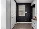 Modern entryway showcasing black accent wall, white door, laminate floors, and stylish white dresser at 14175 W Bronco Trl, Surprise, AZ 85387