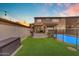 Well-maintained backyard with artificial turf, a pool, and patio with a grill at 14875 W Larkspur Dr, Surprise, AZ 85379