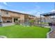Expansive backyard featuring artificial turf, a pool, patio areas, and palm trees at 14875 W Larkspur Dr, Surprise, AZ 85379