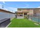 Spacious backyard featuring artificial turf, a pool with safety fence, and a covered patio at 14875 W Larkspur Dr, Surprise, AZ 85379