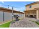A backyard featuring a stone-paved patio, a grill, an umbrella, and a covered patio with chairs and a table at 14875 W Larkspur Dr, Surprise, AZ 85379
