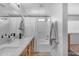 Bright bathroom features a double sink vanity with white countertop, shower-tub combo with white curtain, and window at 14875 W Larkspur Dr, Surprise, AZ 85379