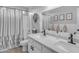 Bathroom featuring double sink vanity, framed mirror, shower-tub combo with curtains, and stylish decorations for a clean aesthetic at 14875 W Larkspur Dr, Surprise, AZ 85379