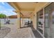 Covered patio area featuring stone pavers, outdoor seating, and a sliding glass door at 14875 W Larkspur Dr, Surprise, AZ 85379
