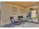 Covered patio with a table, chairs, checkered pillows, and an exterior wall with windows at 14875 W Larkspur Dr, Surprise, AZ 85379